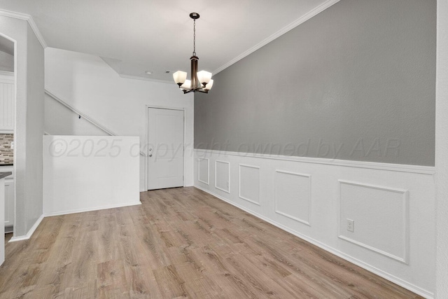 9909 Asher Ave, Amarillo, TX 79119 - unfurnished dining area with crown molding, a chandelier, wood finished floors, wainscoting, and a decorative wall