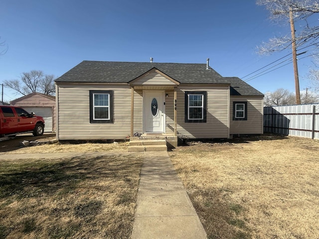 bungalow with an outbuilding, a garage, and a front lawn