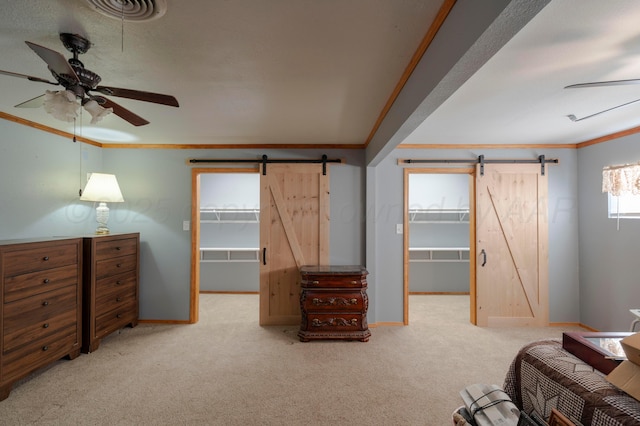 carpeted bedroom with a walk in closet, crown molding, and a barn door