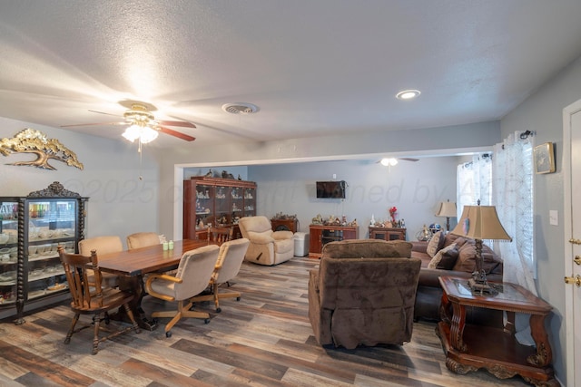 dining space with ceiling fan, wood-type flooring, and a textured ceiling