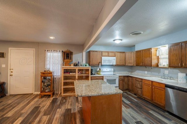 kitchen with sink, white appliances, dark hardwood / wood-style floors, a textured ceiling, and a kitchen island