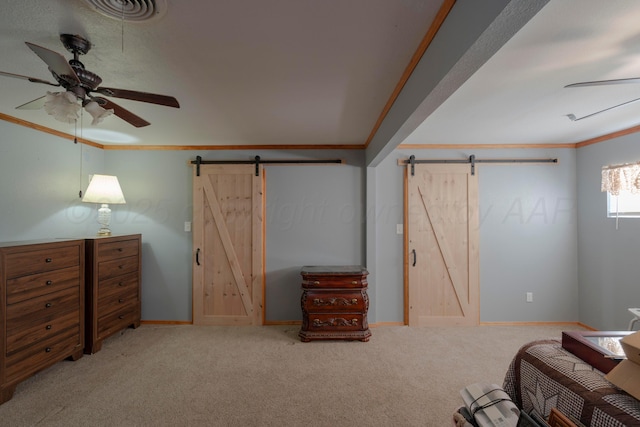 sitting room with ornamental molding, a barn door, ceiling fan, and carpet