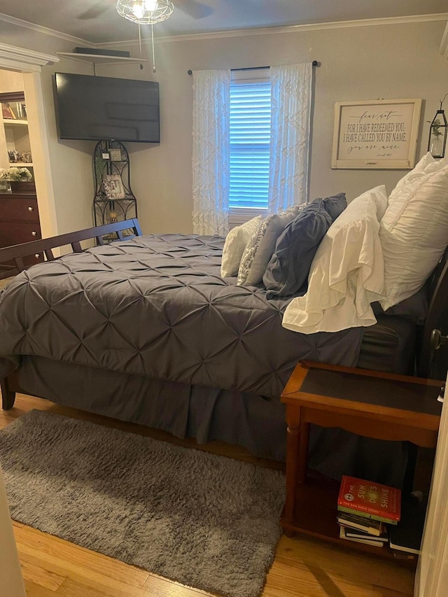 bedroom with ornamental molding and wood finished floors