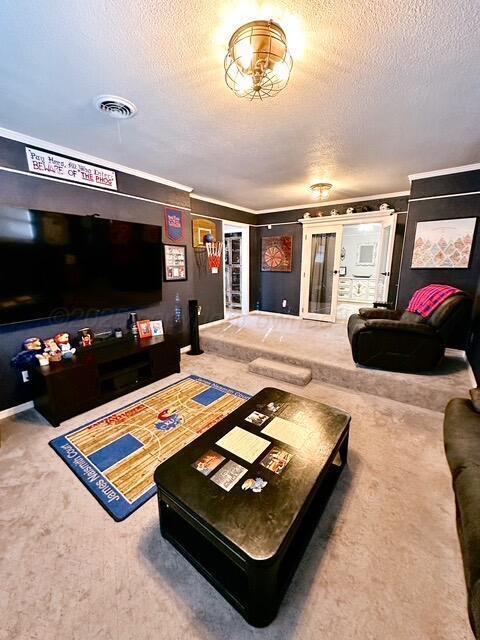 home theater room with carpet floors, crown molding, visible vents, and a textured ceiling