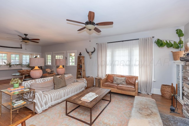 living room featuring ceiling fan, a fireplace, wood finished floors, and baseboards