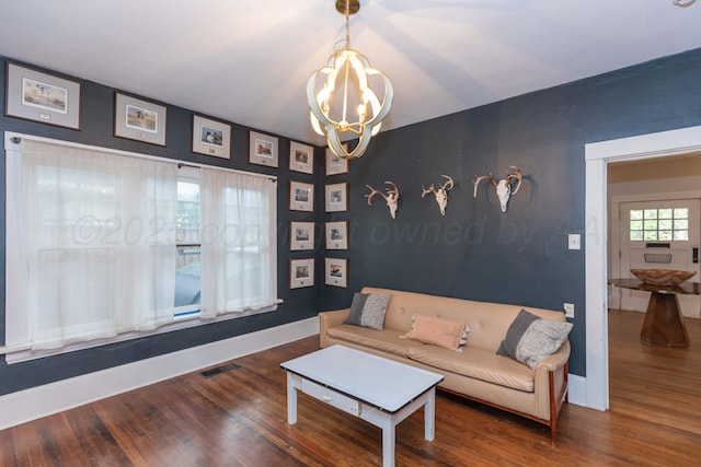 living area featuring a chandelier, wood finished floors, and baseboards
