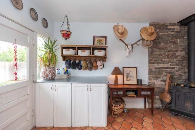 kitchen with a wood stove, white cabinets, light countertops, and open shelves