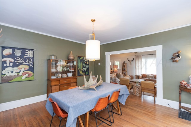 dining room featuring wood finished floors, ornamental molding, and baseboards