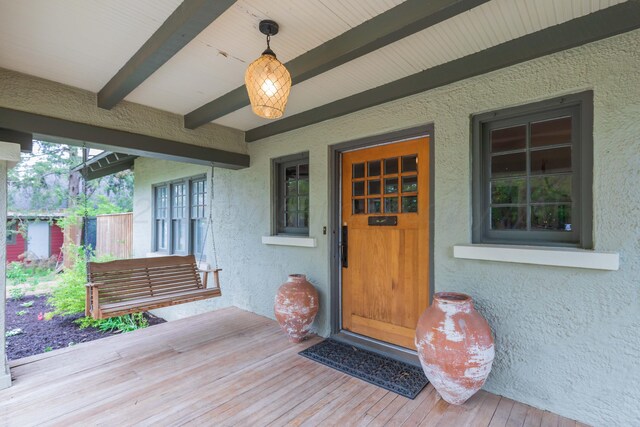 doorway to property with stucco siding and covered porch