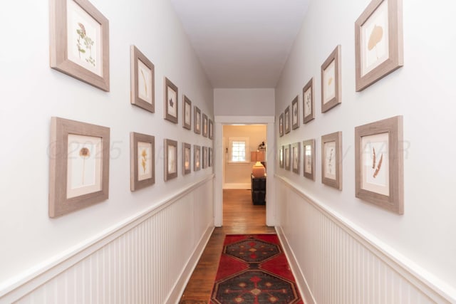 hallway featuring dark wood-style floors and a wainscoted wall