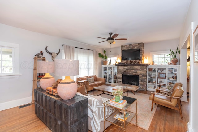 living area with a ceiling fan, wood finished floors, a fireplace, and baseboards