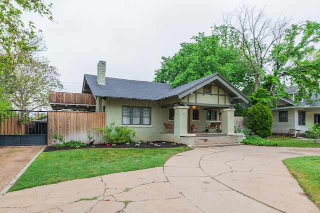 view of front of home featuring stucco siding, a chimney, covered porch, a shingled roof, and concrete driveway