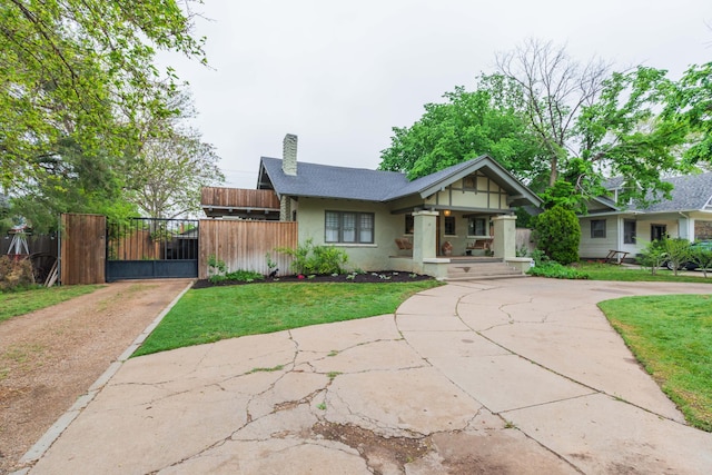 view of front of home featuring curved driveway, a porch, stucco siding, a chimney, and a gate