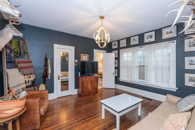 living area with a chandelier, dark wood-type flooring, and baseboards