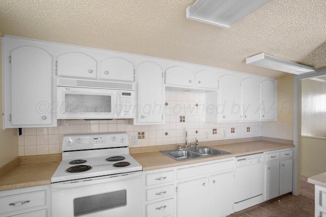 kitchen featuring light countertops, a textured ceiling, a sink, and white appliances