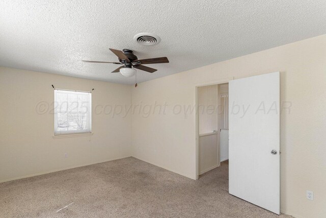 carpeted empty room featuring a ceiling fan, a textured ceiling, and visible vents