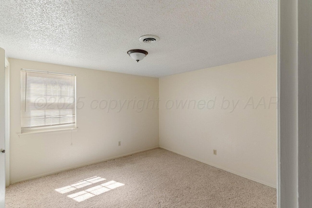 carpeted spare room with visible vents and a textured ceiling