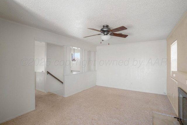 carpeted spare room with a ceiling fan, a textured ceiling, ornamental molding, and a fireplace