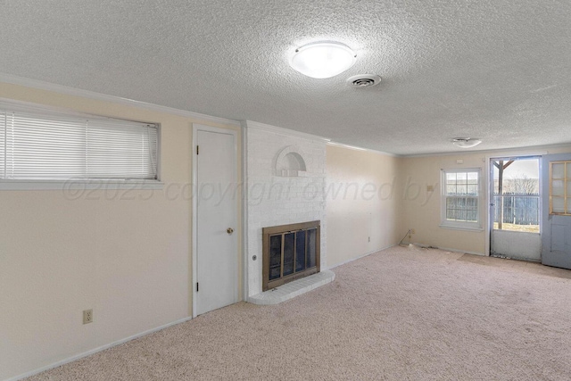 unfurnished living room featuring carpet flooring, a textured ceiling, visible vents, a fireplace, and ornamental molding