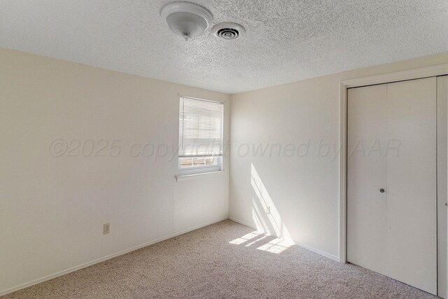 unfurnished bedroom with carpet flooring, a textured ceiling, visible vents, and a closet
