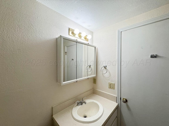 bathroom featuring a textured wall, vanity, and a textured ceiling