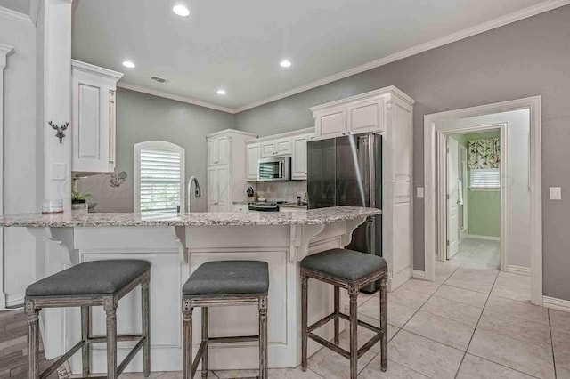 kitchen featuring stainless steel appliances, crown molding, a peninsula, light stone counters, and recessed lighting