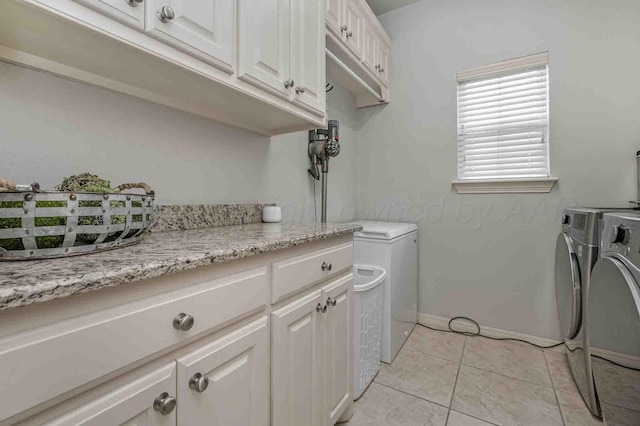 laundry room featuring washing machine and clothes dryer, cabinet space, light tile patterned floors, and baseboards