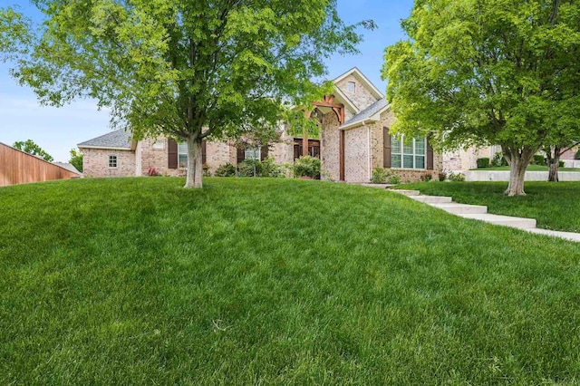 view of property hidden behind natural elements featuring brick siding and a front yard