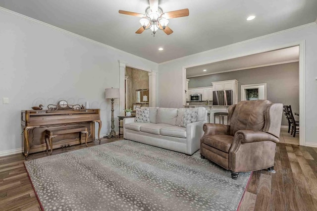living area featuring ornamental molding, baseboards, wood finished floors, a ceiling fan, and recessed lighting