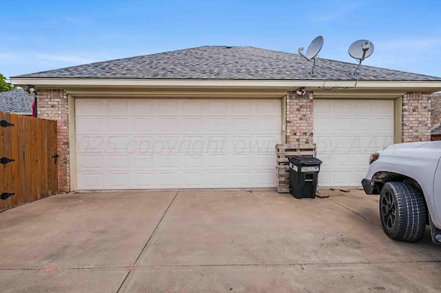 garage featuring concrete driveway and fence