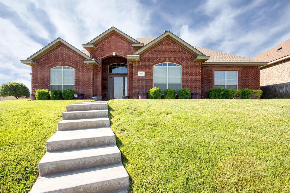 ranch-style home with a shingled roof, a front yard, and brick siding