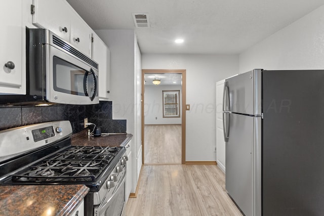 431 Crest, Pampa, TX 79065 - kitchen with appliances with stainless steel finishes, dark countertops, light wood-type flooring, white cabinets, and decorative backsplash