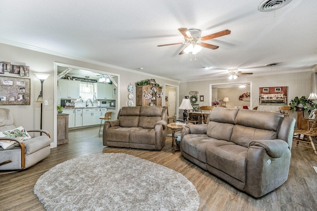 227 Ranger St, Hereford, TX 79045 - living room featuring a ceiling fan, wood finished floors, ornamental molding, and a textured ceiling