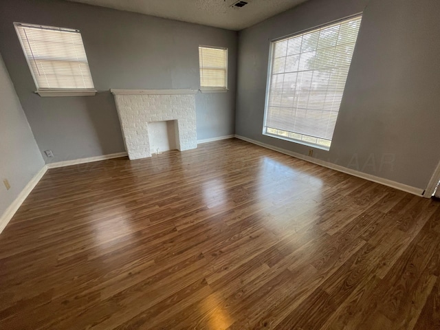 unfurnished living room with a textured ceiling, dark wood-type flooring, a fireplace, and baseboards