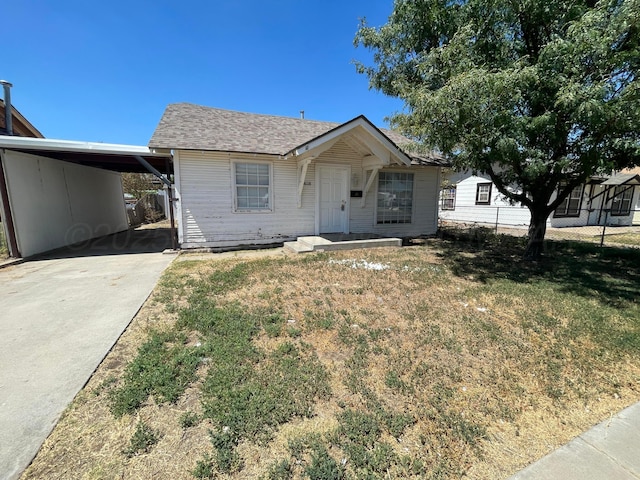 view of front of home with driveway, an attached carport, a front yard, and a shingled roof