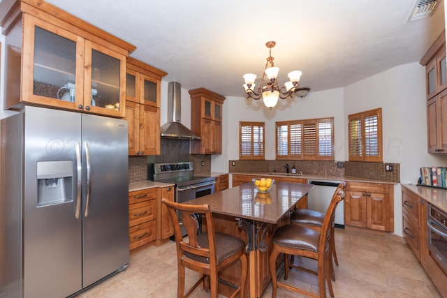3616 Van Tassel St, Amarillo, TX 79121 - kitchen featuring appliances with stainless steel finishes, wall chimney range hood, a chandelier, brown cabinetry, and tasteful backsplash