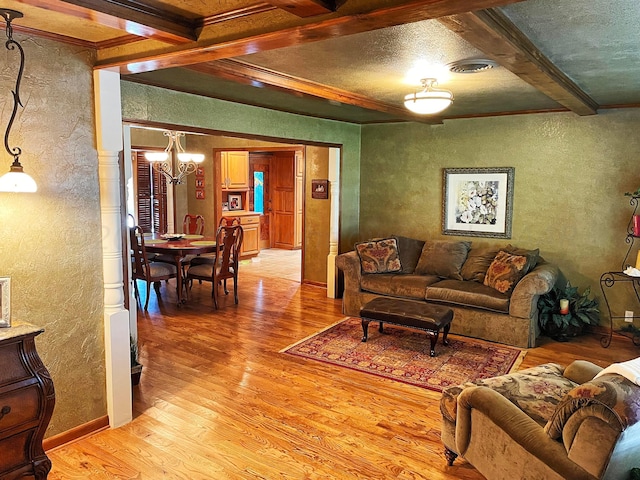 living room featuring an inviting chandelier, beam ceiling, light hardwood / wood-style floors, and crown molding