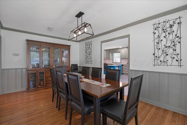 100 S Avondale St, Amarillo, TX 79106 - dining area featuring light wood-type flooring, crown molding, a decorative wall, and a wainscoted wall