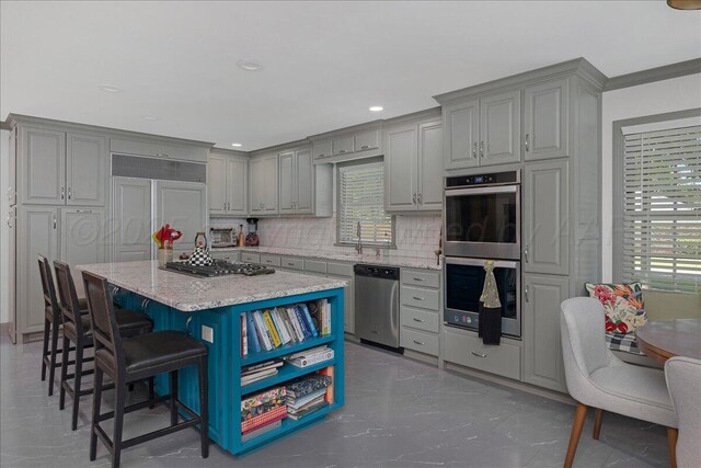 100 S Avondale St, Amarillo, TX 79106 - kitchen with appliances with stainless steel finishes, gray cabinetry, a kitchen breakfast bar, tasteful backsplash, and light stone countertops