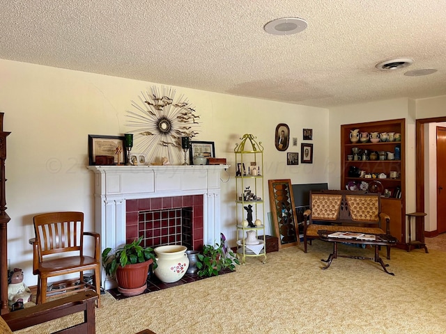 living room with a tiled fireplace, a textured ceiling, and carpet floors