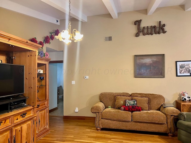 living room with beamed ceiling, a chandelier, and light wood-type flooring