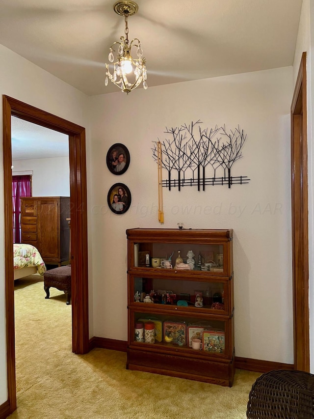 hallway with light carpet and a chandelier