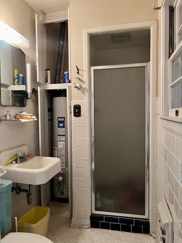 bathroom with tile walls, a textured ceiling, an enclosed shower, tile patterned flooring, and gas water heater