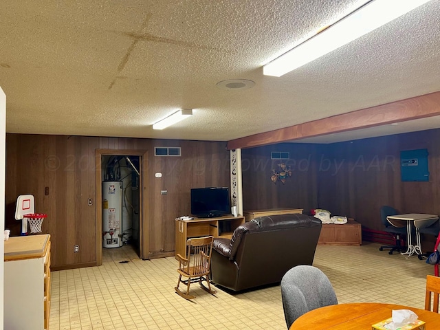 living room featuring water heater, wooden walls, and a textured ceiling