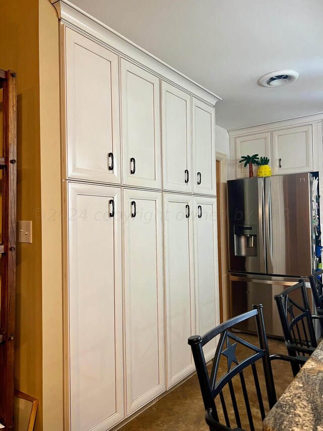 1814 N Main St, Shamrock, TX 79079 - kitchen with stainless steel fridge with ice dispenser, white cabinetry, and dark stone counters
