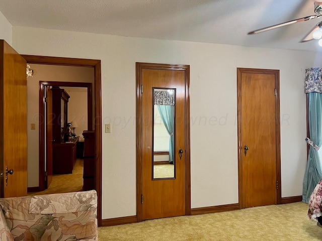 bedroom featuring ceiling fan, a textured ceiling, and light colored carpet