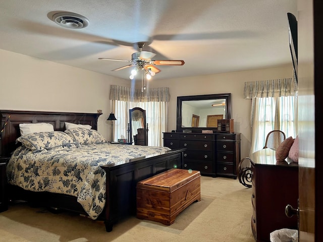 bedroom featuring ceiling fan, a textured ceiling, and light carpet