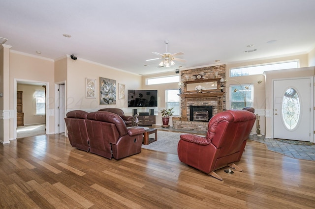 living room featuring light wood-type flooring, ornamental molding, and a brick fireplace