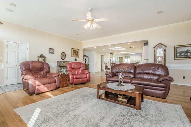 living room with ceiling fan, light wood-type flooring, and ornamental molding