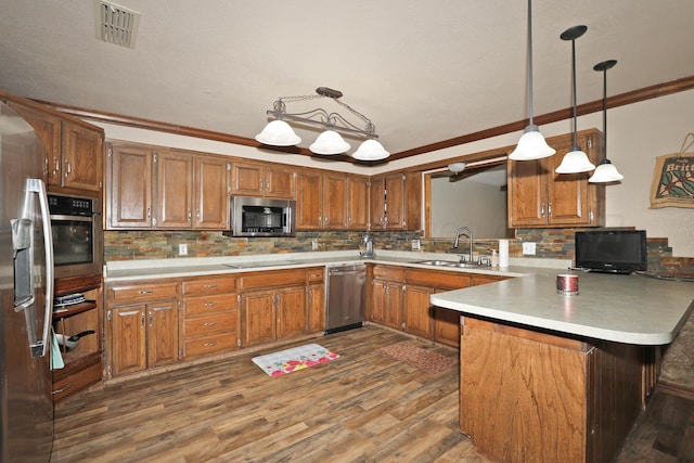 kitchen with visible vents, appliances with stainless steel finishes, brown cabinets, a sink, and a peninsula